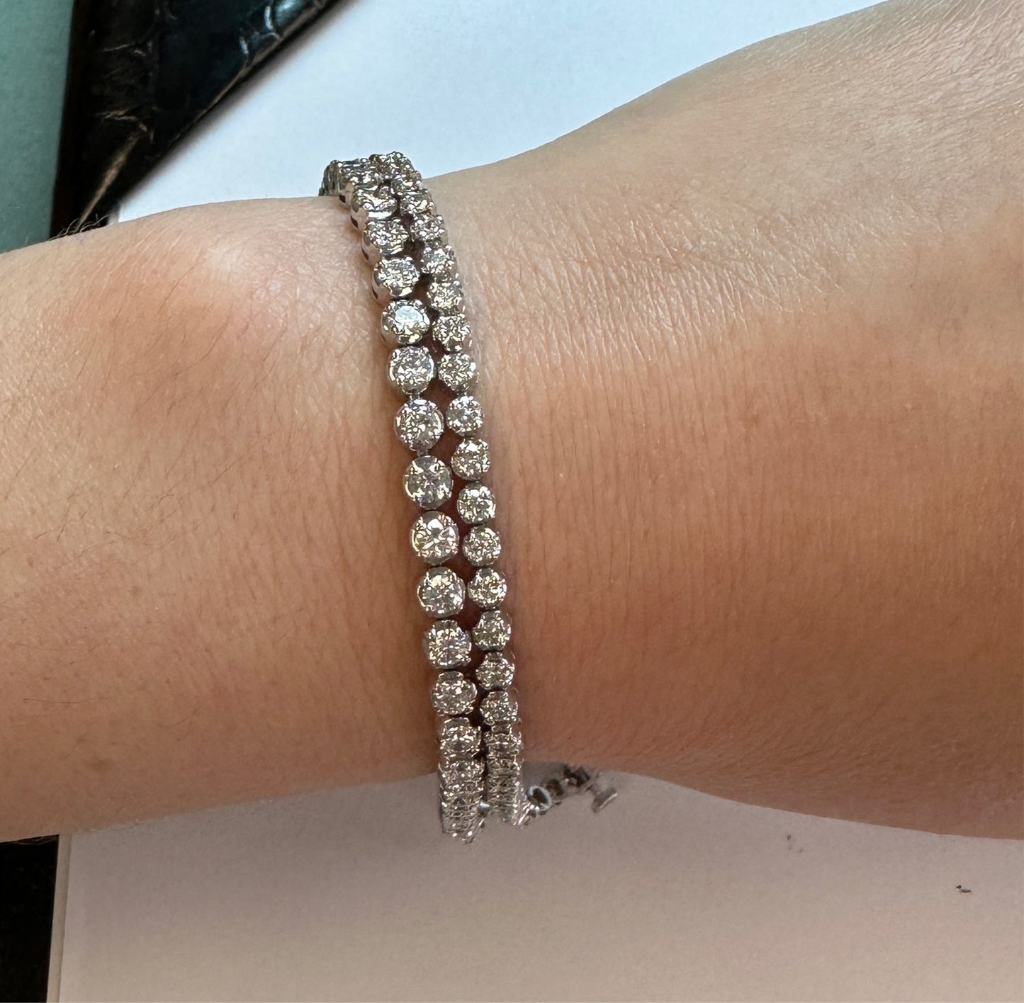 A woman's wrist with a 2.5ct lab grown diamond tennis bracelet and a 4ct lab grown diamond tennis bracelet.